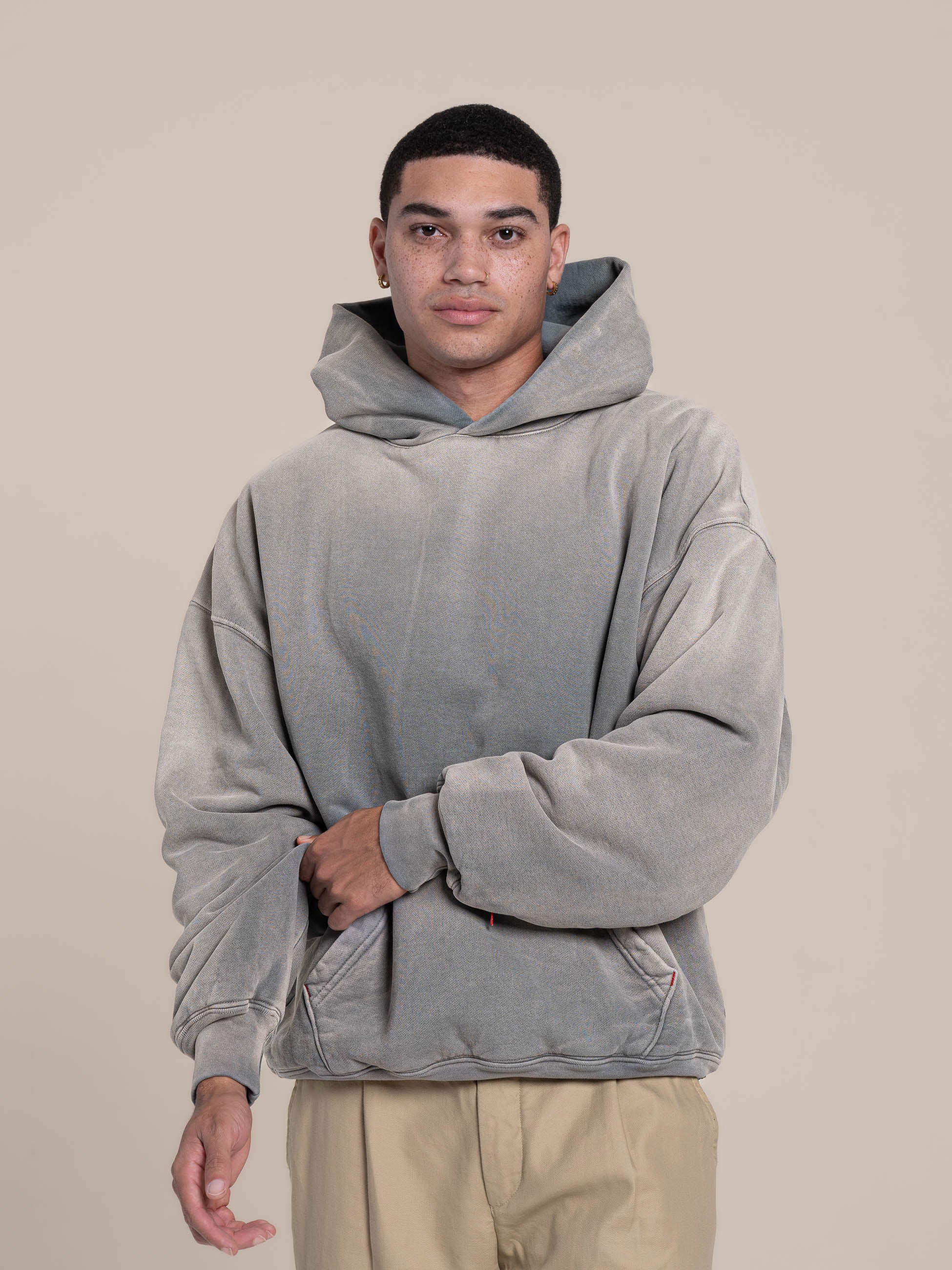 Male Model pulls double layered hoodie ash blue  right arm sleeve