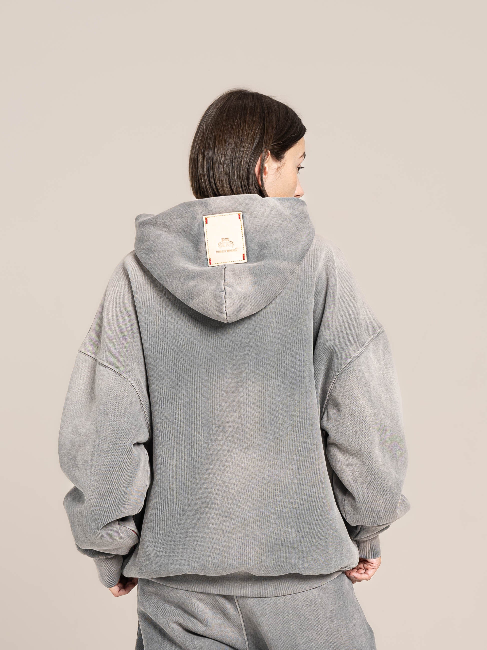 Female model shows a detail of the double layered fleece ash blue hoodie back side