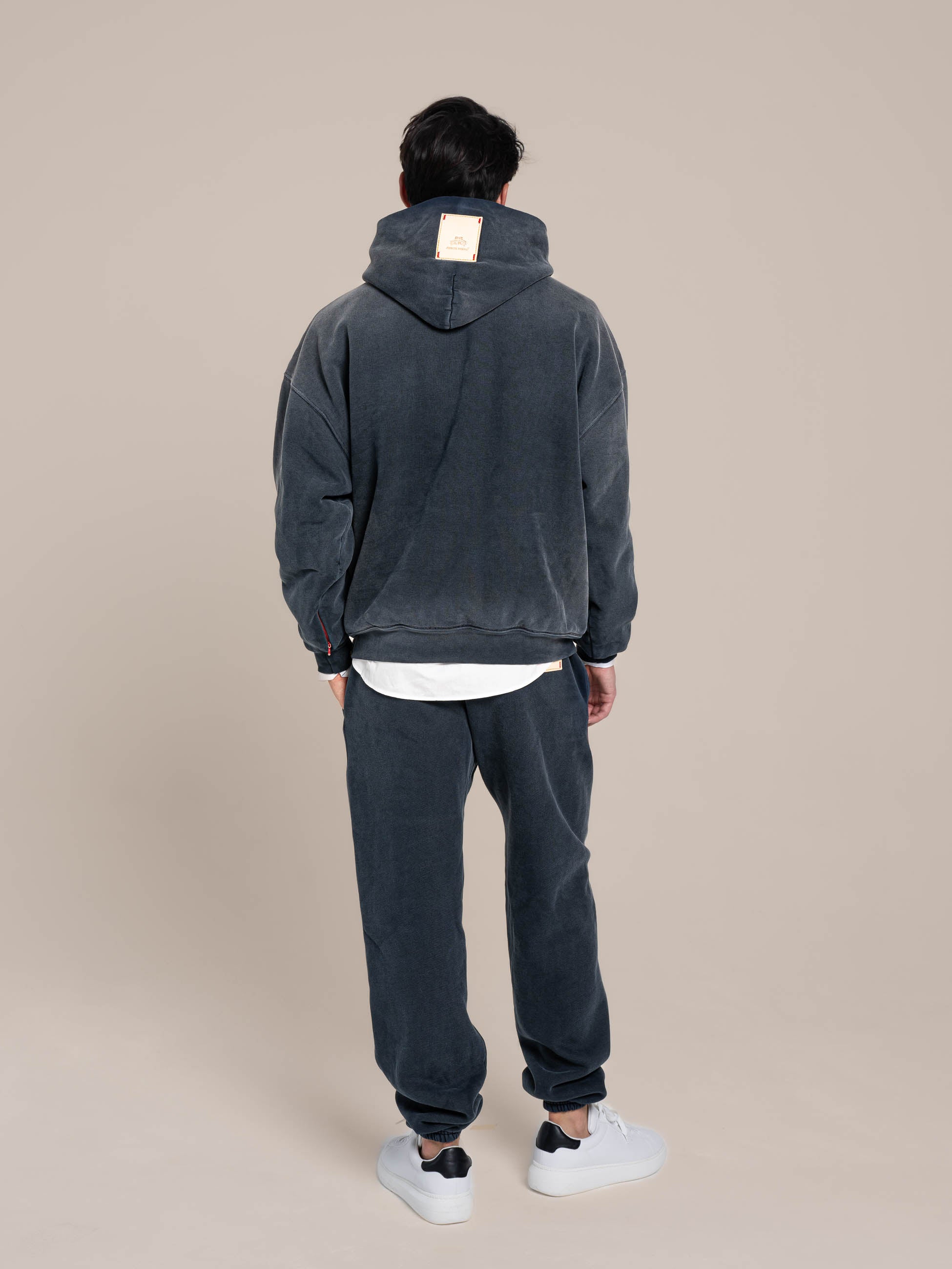 Male model shows details on the back of the navy hoodie and navy sweatpants Made in USA