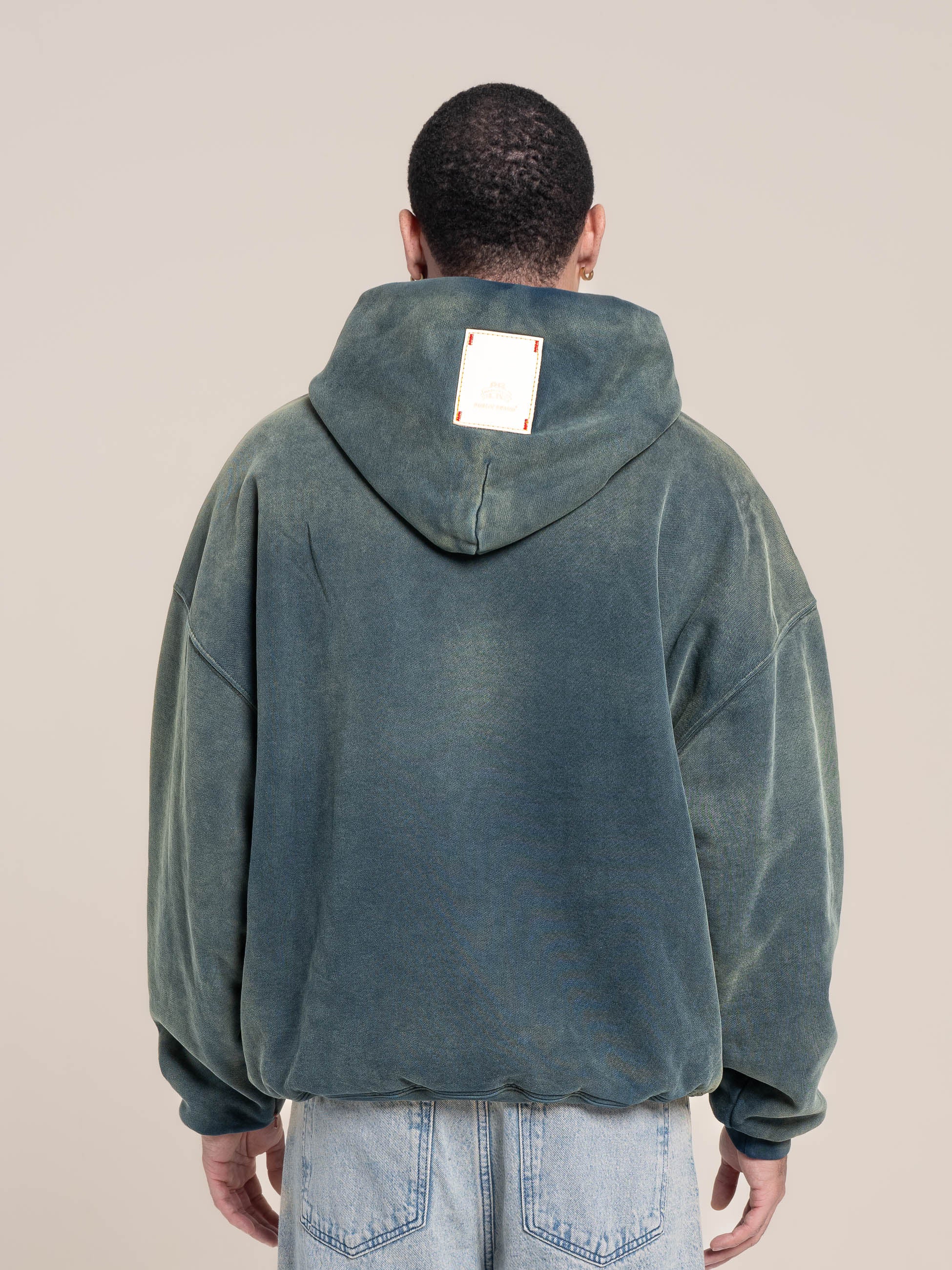 male model shows  a detail of the back of the double layered fleece indigo hoodie