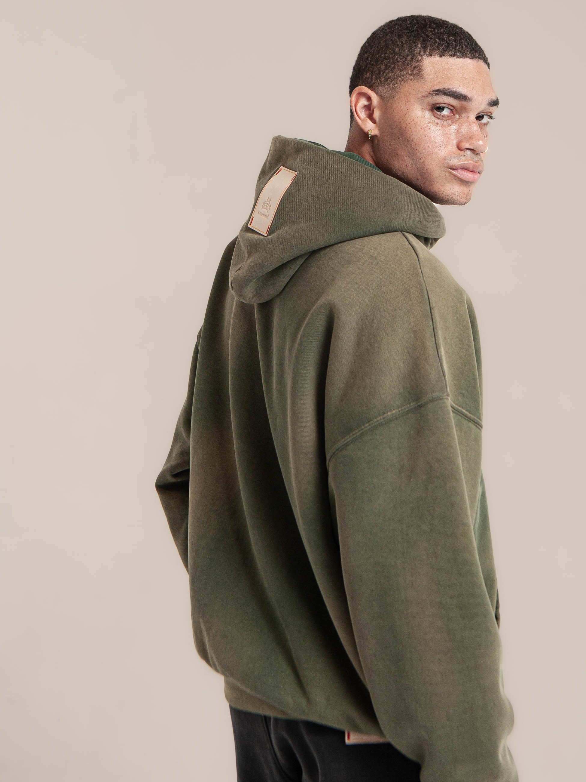 male model wears Publik Brand Double Layered Hoodie Reseda Green Heavyweight Fleece, all made in USA, turning around and looking for the view
