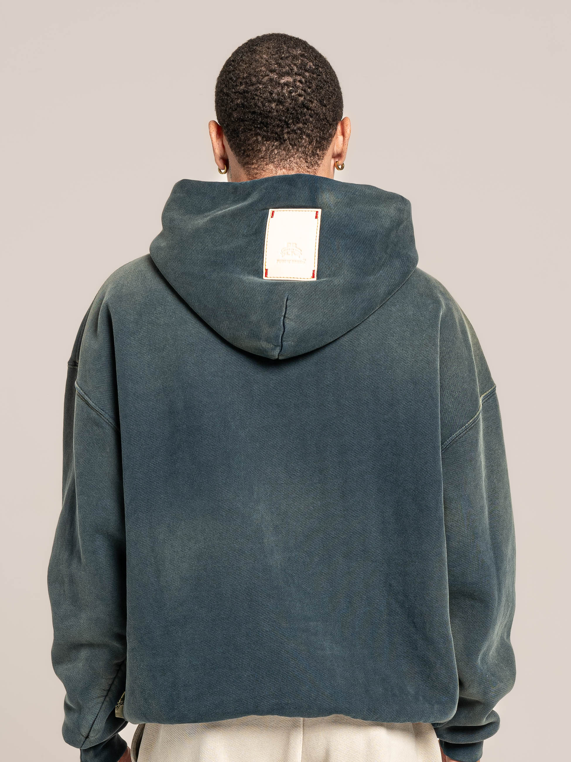 Male model wears Publik Brand Single Layered Hoodie Indigo Heavyweight Fleece, all made in USA, back side