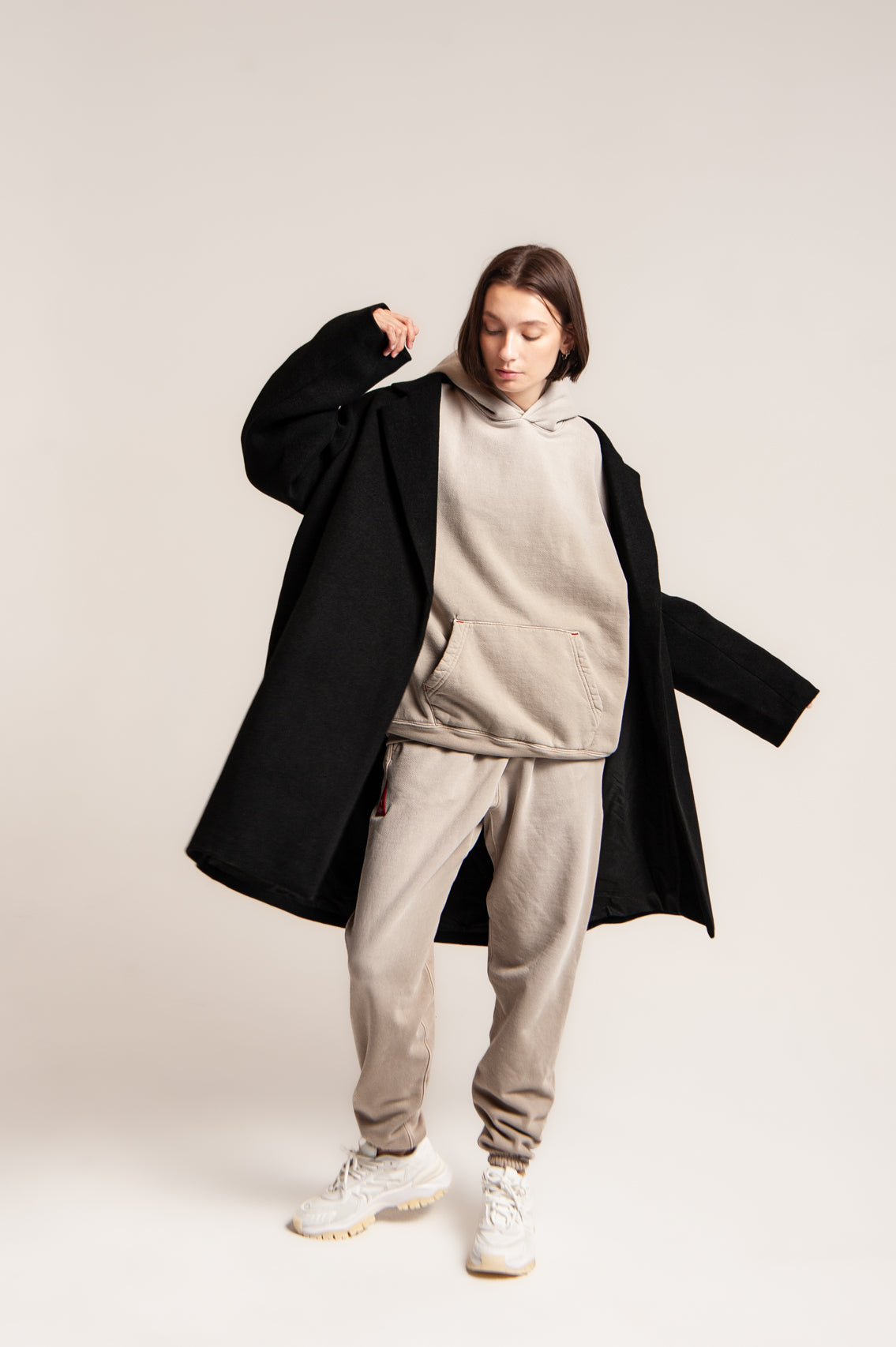 Matching hoodie and sweatpants worn under a long dark coat with white sneakers
